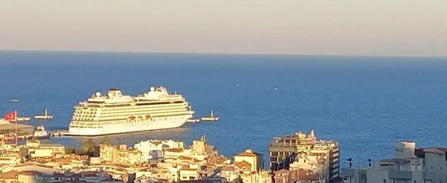 A cruise ship anchored off the Kusadasi coastline at sunset